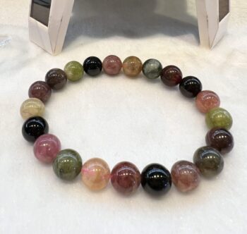 A bracelet of different colored stones on a white surface.