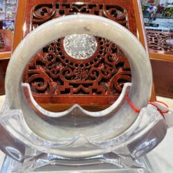 A white and red circular stone display in front of an ornate wooden carving.