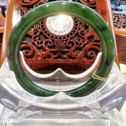 A green bangle sitting on top of a clear plastic container.