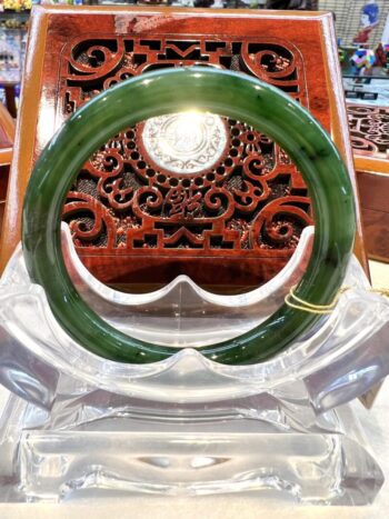 A green bangle sitting on top of a clear plastic container.