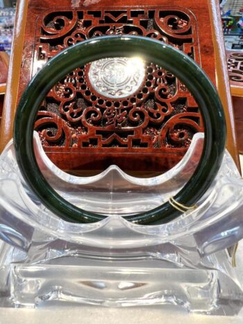 A green bangle sitting on top of a clear plastic container.