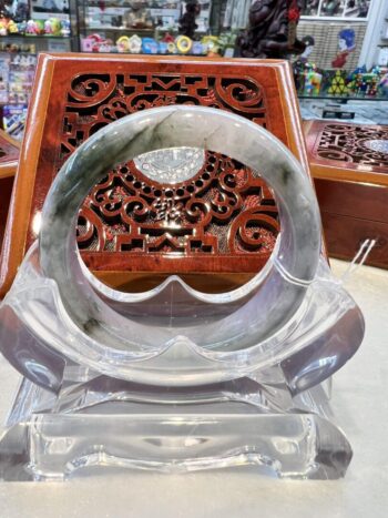 A clear glass sculpture of an object in front of a wooden carving.