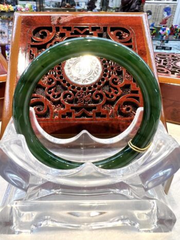 A green bangle sitting on top of a clear glass bowl.