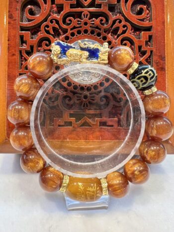 A round mirror with a large orange bead necklace.