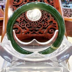 A green bangle sitting on top of a clear plastic container.