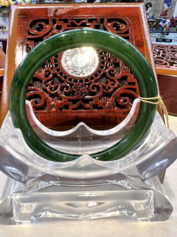 A green and white bangle sitting on top of a clear glass bowl.