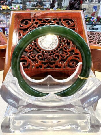 A green jade bangle sitting on top of a wooden chair.