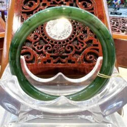 A green jade bangle sitting on top of a clear glass bowl.