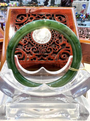 A green jade bangle sitting on top of a clear glass bowl.