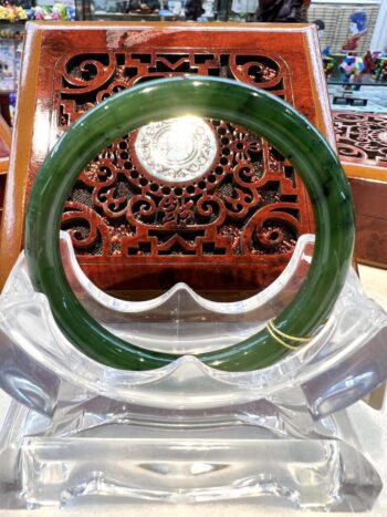 A green bangle sitting on top of a clear plastic holder.