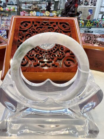 A clear glass sculpture of an object in front of a wooden carving.