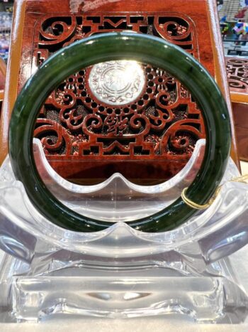 A green bangle sitting on top of a clear chair.