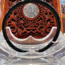 A black and white circular necklace sitting on top of a wooden table.