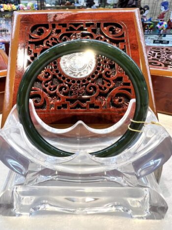 A green bangle sitting on top of a clear chair.