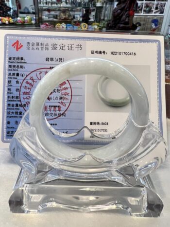 A white bracelet sitting on top of a clear glass display.