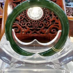 A green bangle sitting on top of a clear glass table.