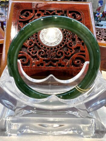 A green bangle sitting on top of a clear glass table.