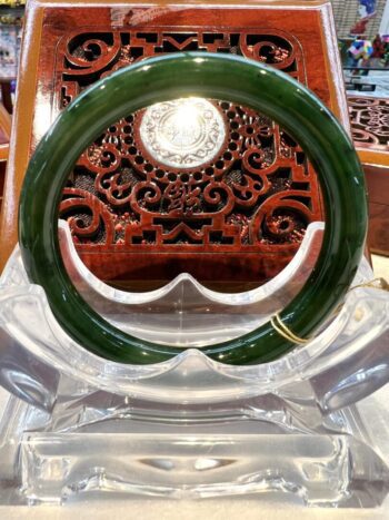 A green bangle sitting on top of a clear glass table.