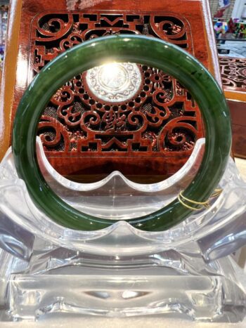 A green bangle sitting on top of a clear glass table.