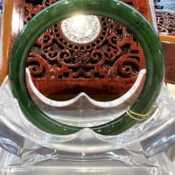 A green bangle sitting on top of a clear glass table.