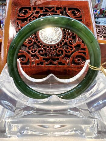 A green bangle sitting on top of a clear glass table.