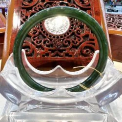 A green jade bangle sitting on top of a clear glass.