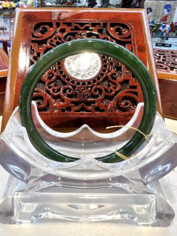 A green jade bangle sitting on top of a clear glass.