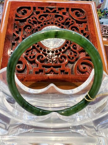 A green jade bangle sitting on top of a wooden table.