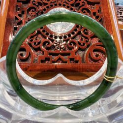 A green jade bangle sitting on top of a wooden table.