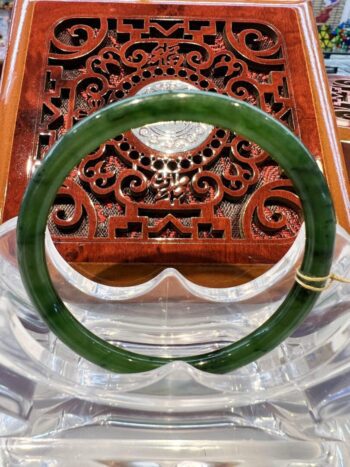 A green jade bangle sitting on top of a wooden table.