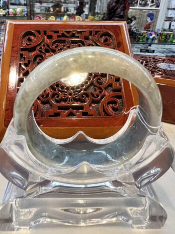 A clear glass bracelet sitting on top of a wooden table.