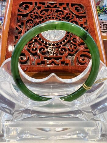 A green bangle sitting on top of a wooden chair.