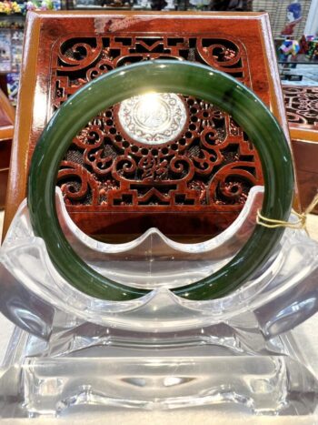 A green jade bangle sitting on top of a clear glass.