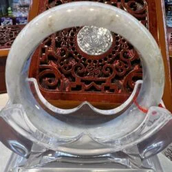 A white jade bracelet sitting on top of a clear glass bowl.