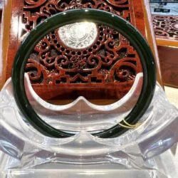 A green bangle sitting on top of a clear plastic holder.