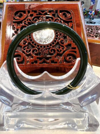 A green bangle sitting on top of a clear plastic holder.