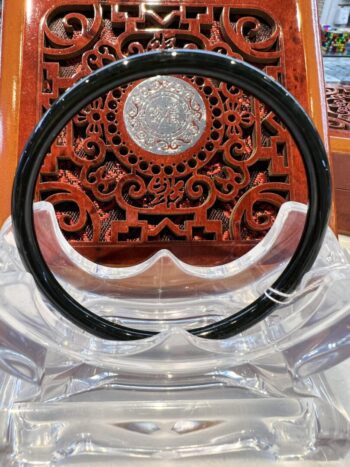 A black and clear plastic chair with a wooden carved wall behind it.