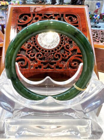 A green jade bangle sitting on top of a clear glass table.