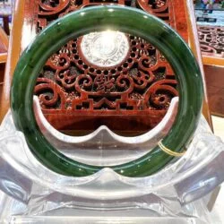 A green jade bangle sitting on top of a clear glass table.