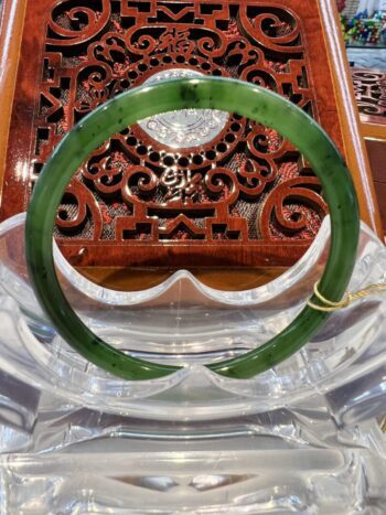 A green jade bangle sitting on top of a wooden table.