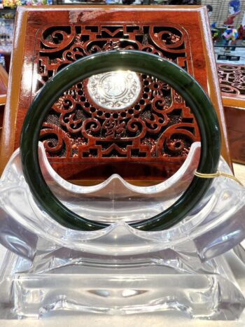 A green jade bangle sitting on top of a clear plastic chair.