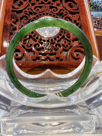 A green jade bangle sitting on top of a wooden chair.