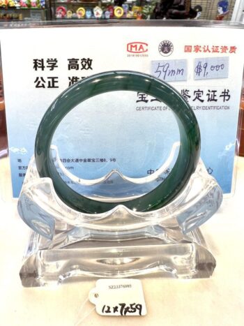 A green jade bangle sitting on top of a clear glass display.