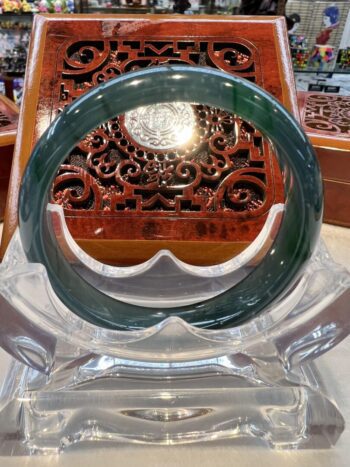 A green jade bangle sitting on top of a clear glass table.