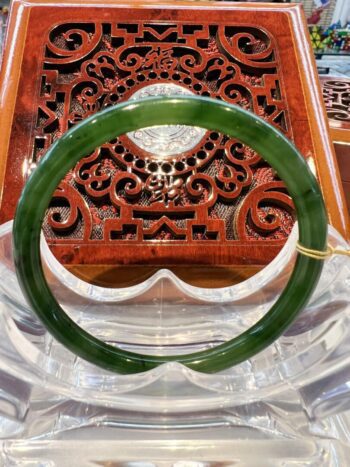 A green jade bangle sitting on top of a wooden table.