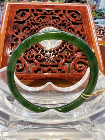 A green jade bangle sitting on top of a wooden box.