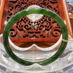 A green jade bangle sitting on top of a wooden table.