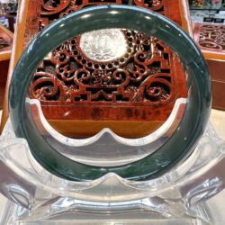 A green jade bangle sitting on top of a clear glass table.