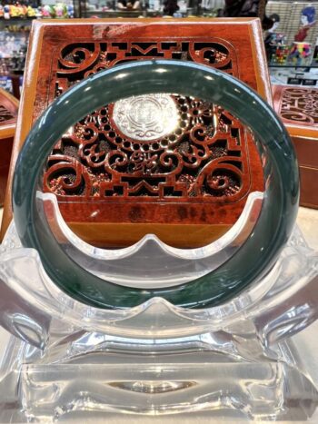 A green jade bangle sitting on top of a clear glass table.