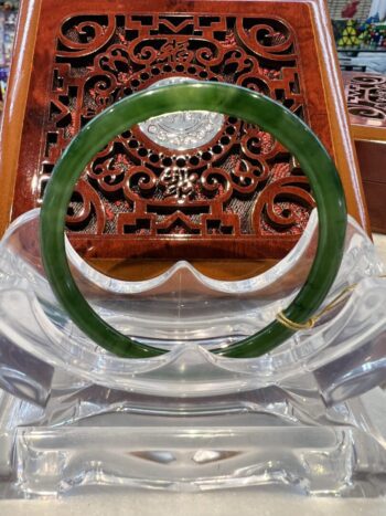 A green jade bangle sitting on top of a clear glass bowl.